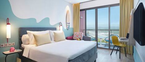 A modern hotel room with a large bed, a desk with a laptop, a chair, and a balcony with a view.