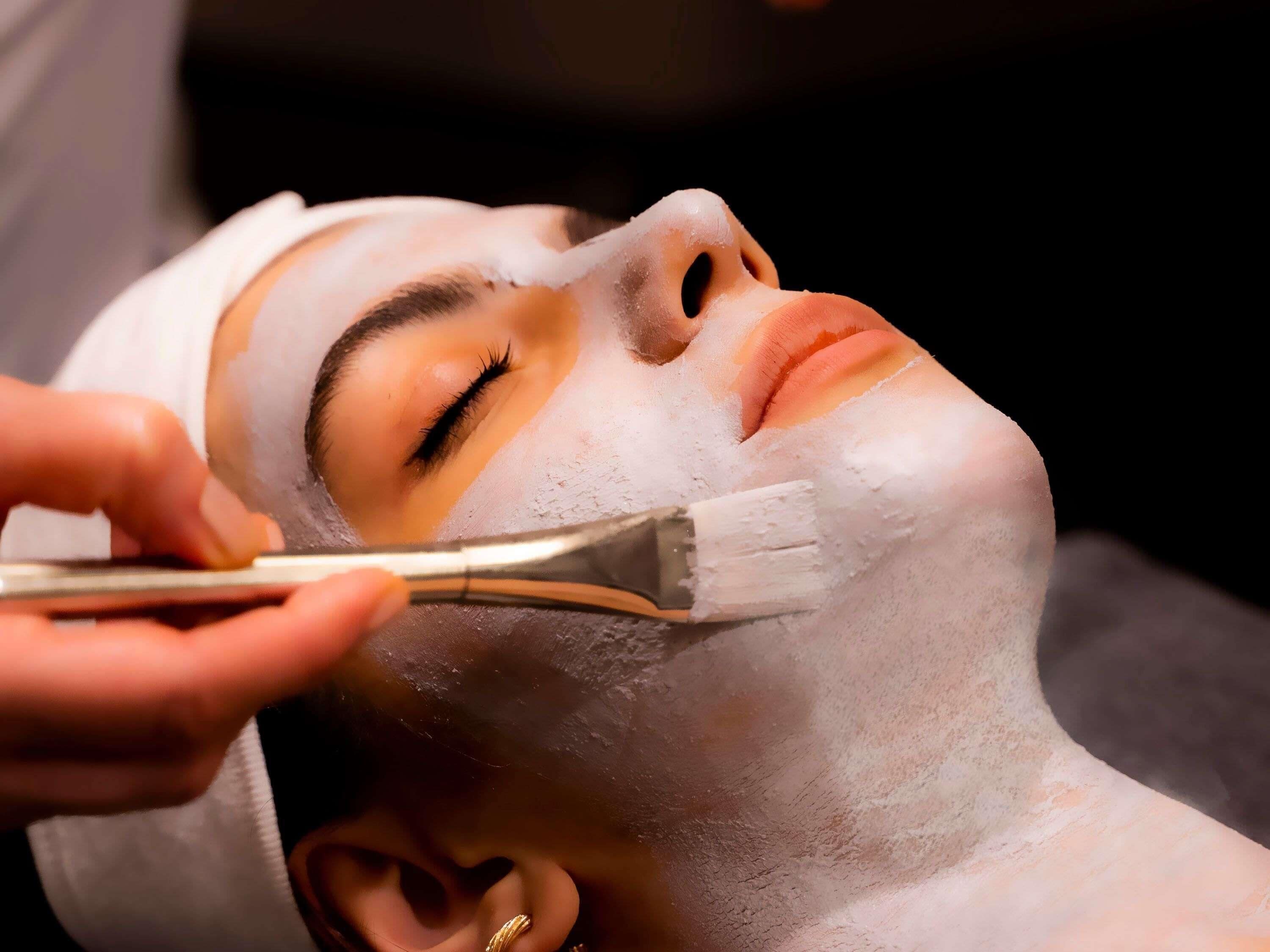 A person receiving a facial treatment with a brush.