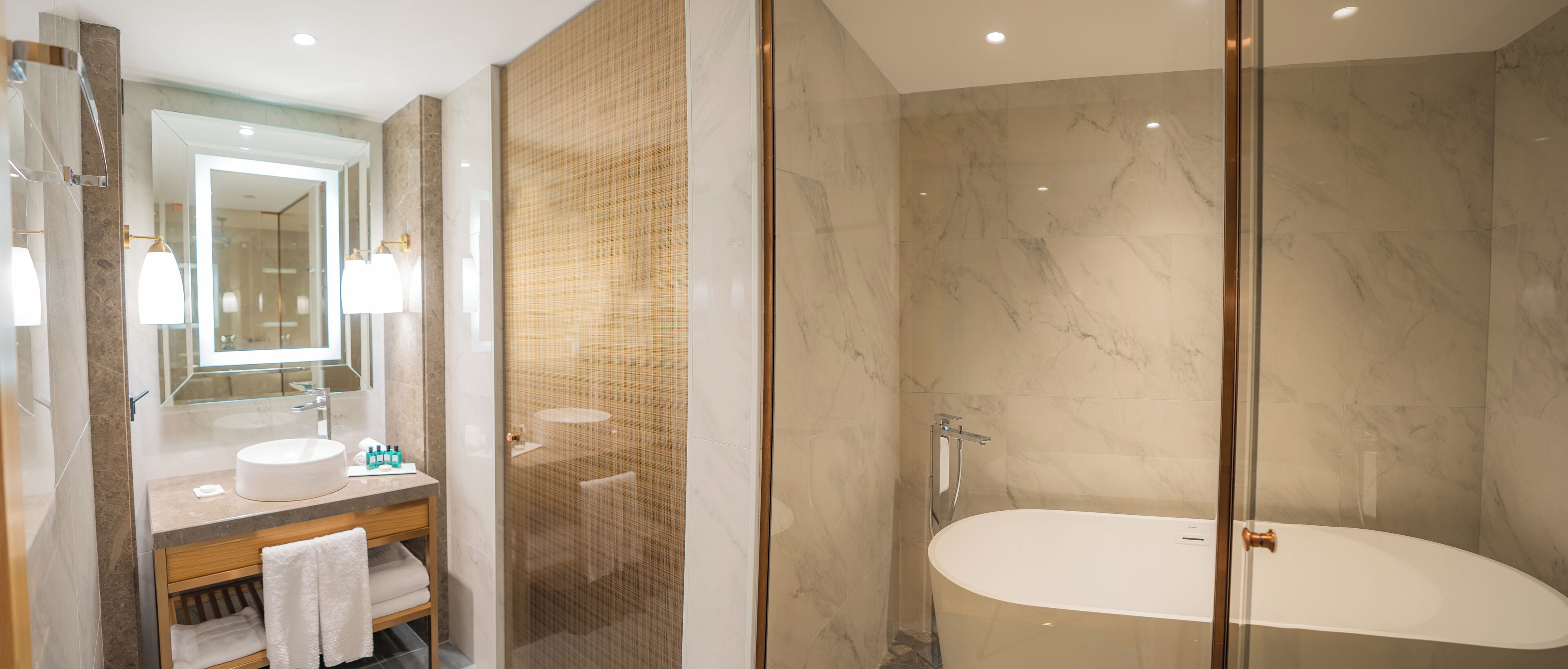 A modern bathroom with a glass-enclosed shower, a vanity with a sink, and a large bathtub.