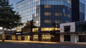 A modern building with a glass facade, a prominent "Pullman" sign on the corner, and a visible entrance with a canopy.
