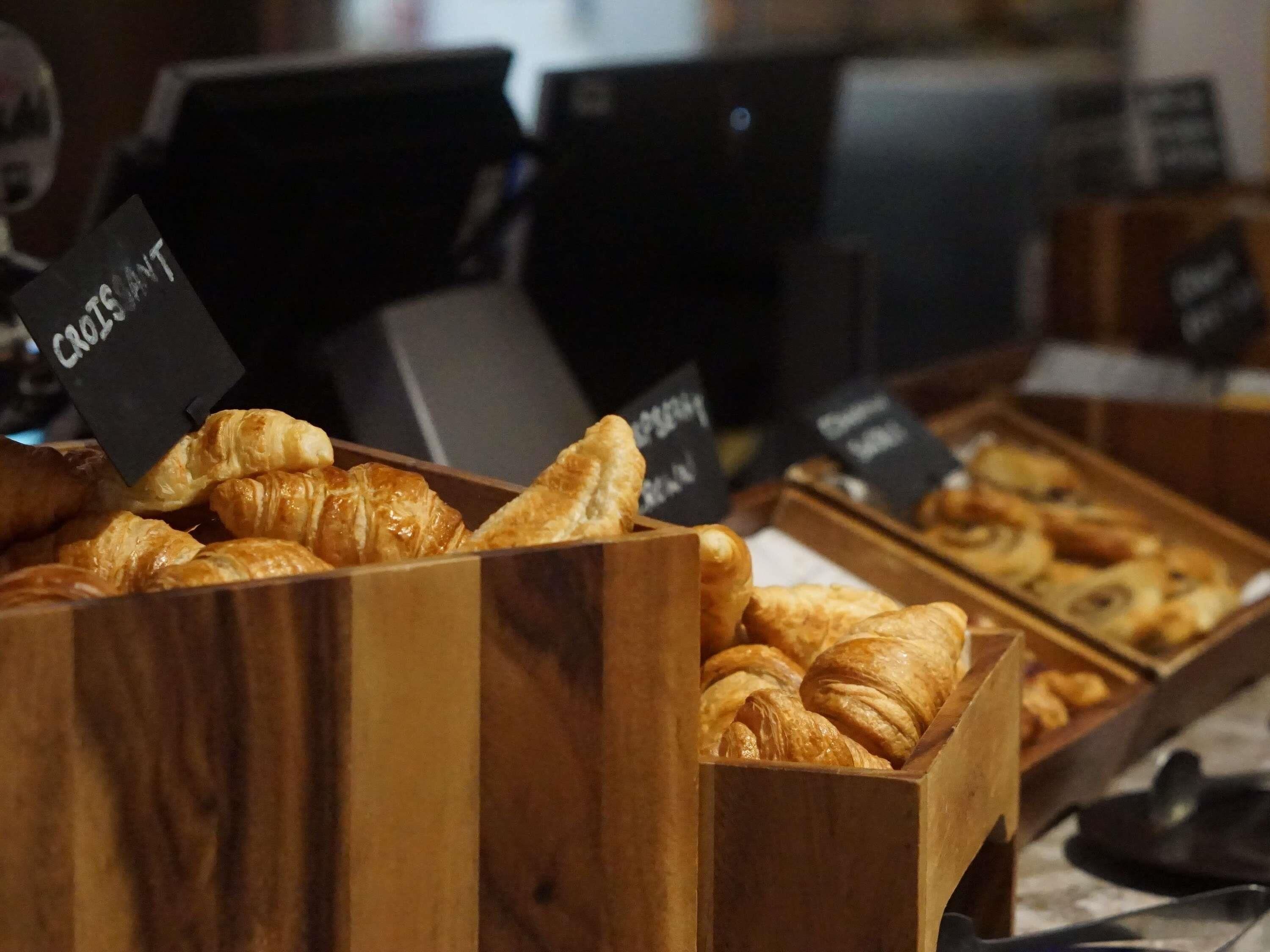 A bakery display with various types of pastries in wooden boxes.