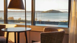 A room with a view of a body of water, a round table, and two chairs.
