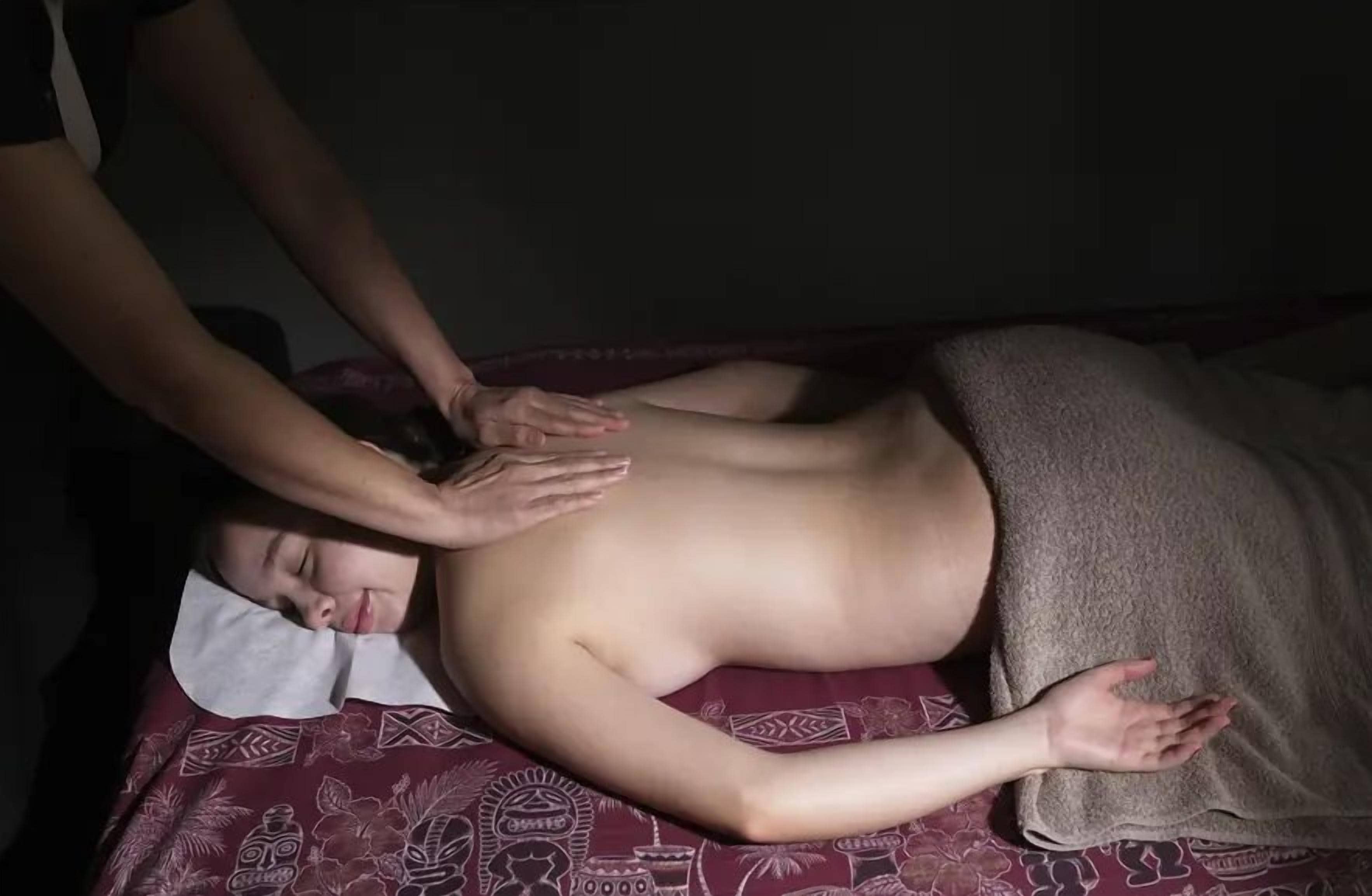 A person lying on a massage table receiving a back massage.