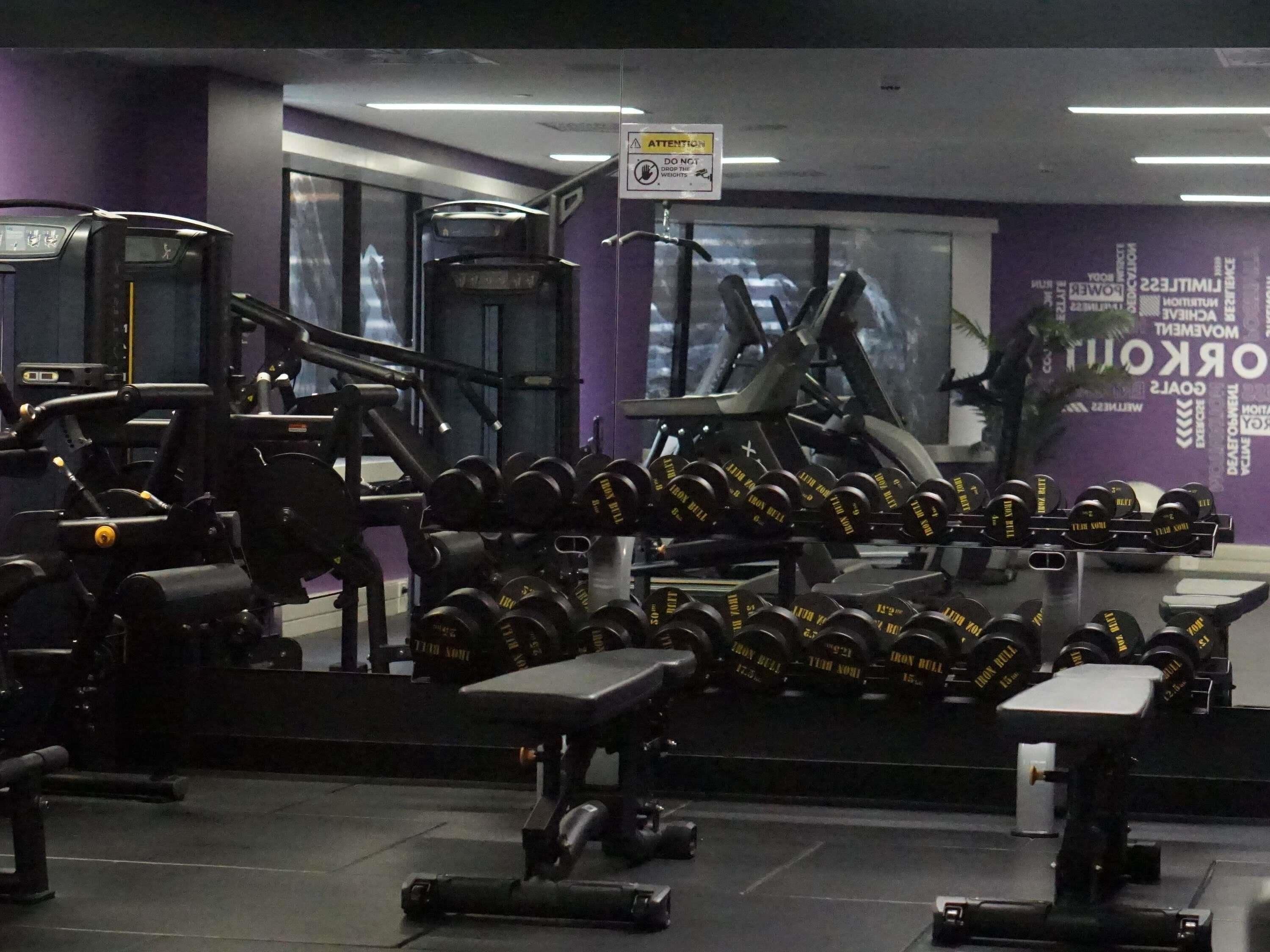 Een sportschool met diverse fitnessapparaten, waaronder gewichten en krachtapparaten.