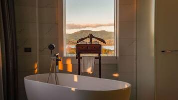 Un baño con una bañera independiente, un ventanal con vistas al paisaje y un perchero para toallas.