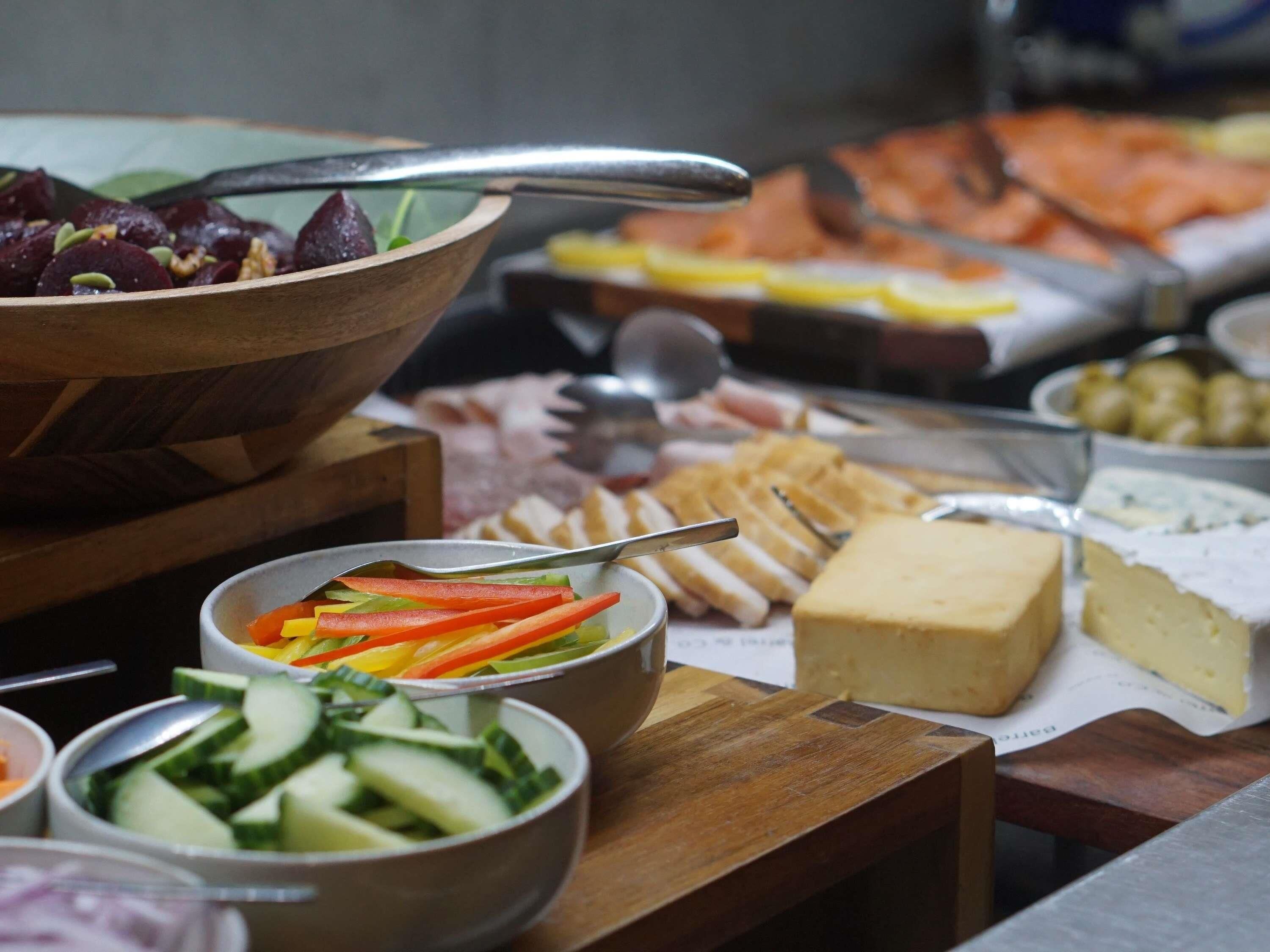 Un bufé con diversas opciones de comida, incluyendo carnes frías, quesos y verduras.