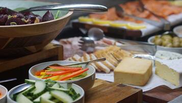 Un bufé con diversas opciones de comida, incluyendo carnes frías, quesos y verduras.