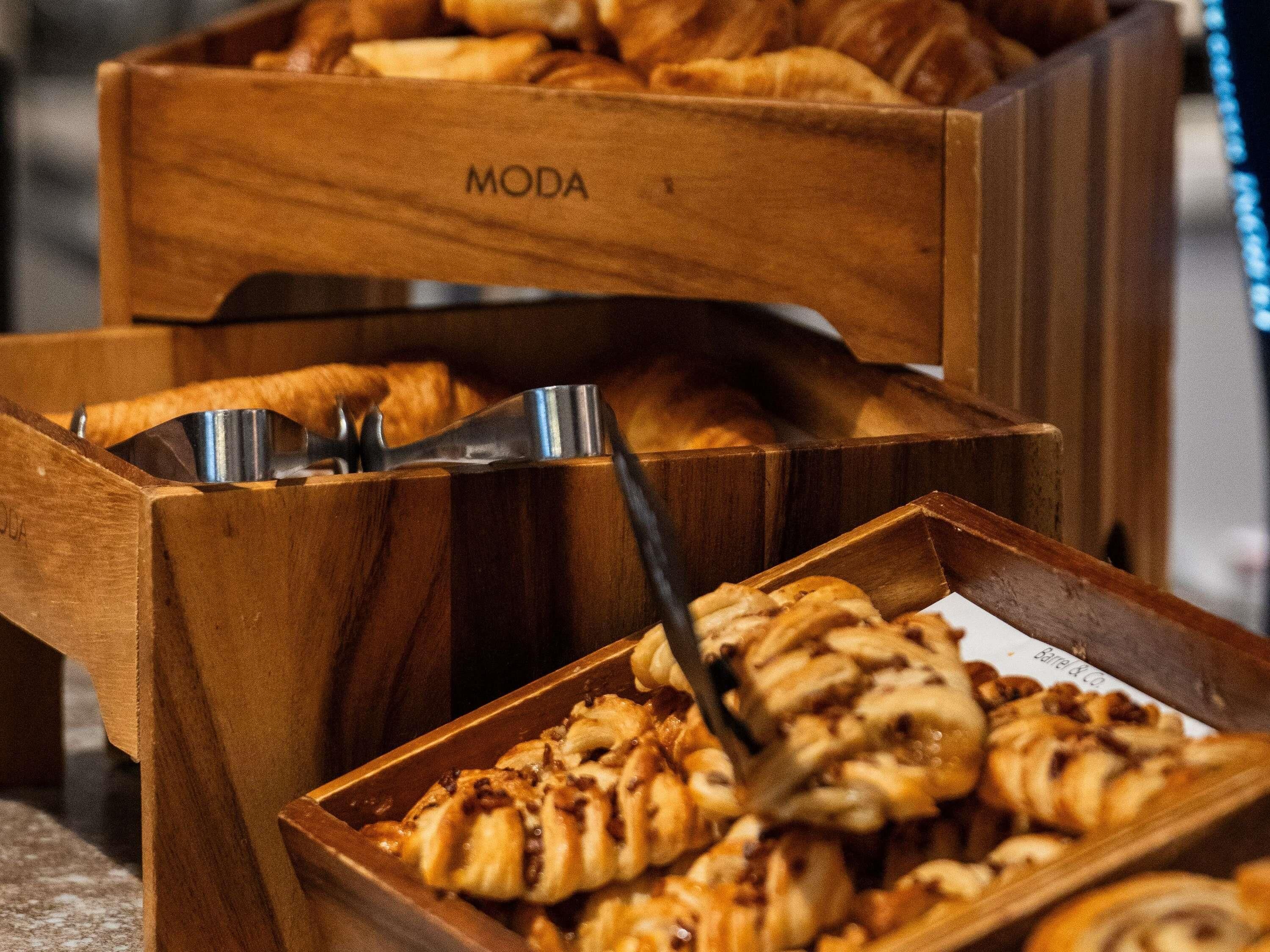 Wooden boxes with baked goods, including pastries and bread, arranged for serving.
