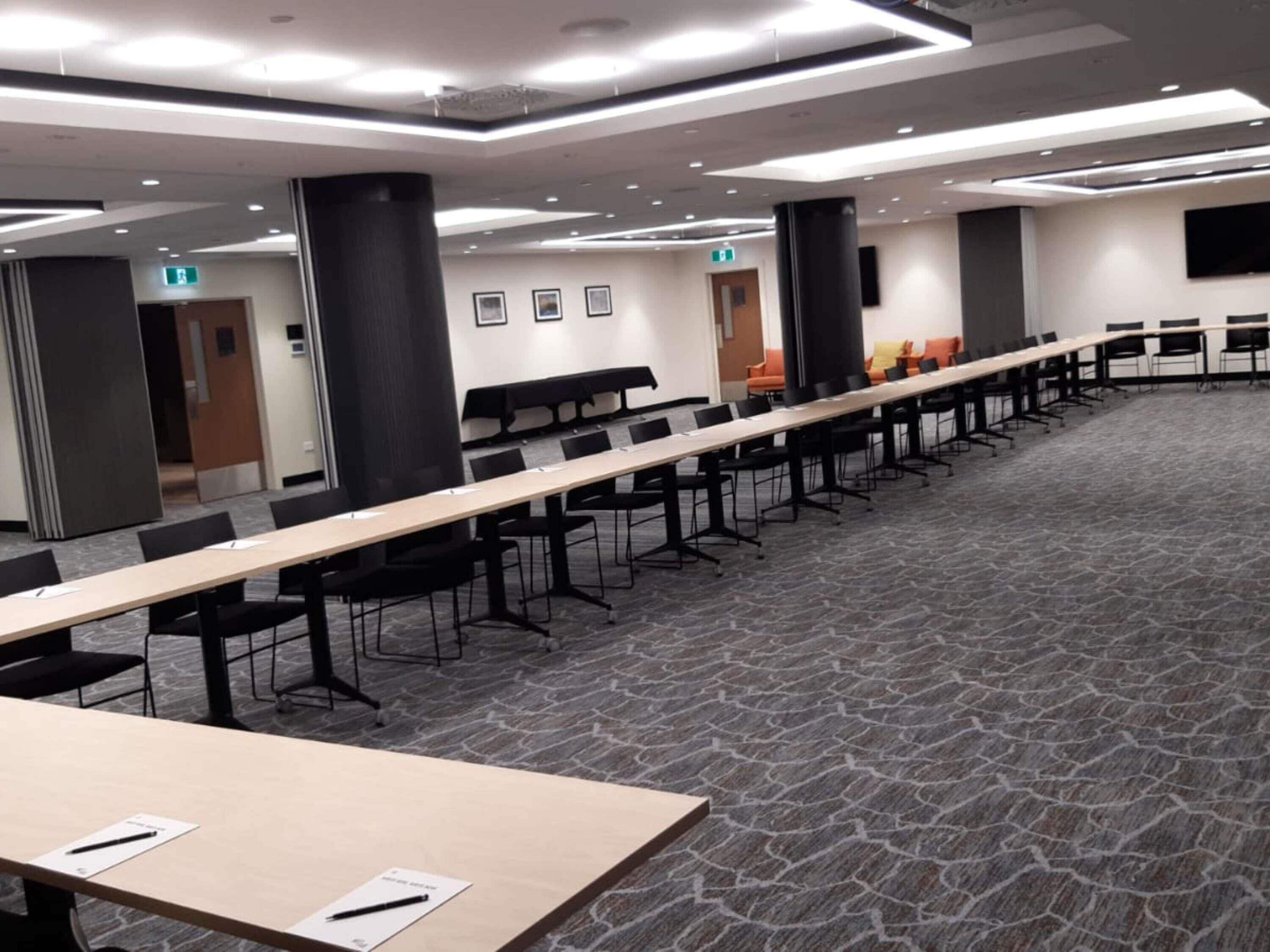A conference room with a long table, chairs, and a carpeted floor.
