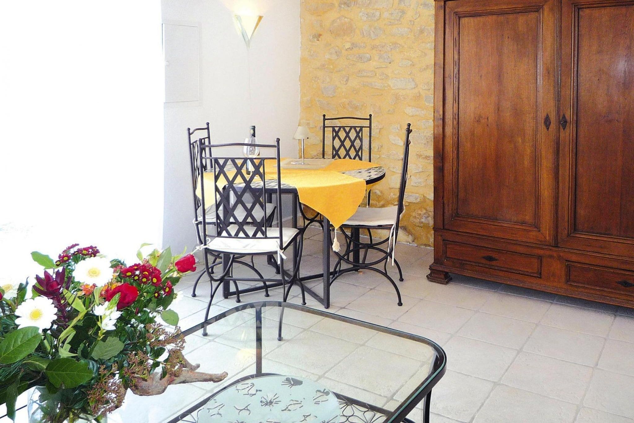 A dining area with a table and chairs, a cabinet, and a glass table with a plant.