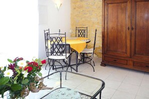 A dining area with a table and chairs, a cabinet, and a glass table with a plant.