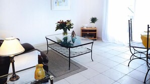 A living room with a glass coffee table, a sofa, a lamp, and a small plant. - Apartment in Caderousse with Pool (Caderousse)