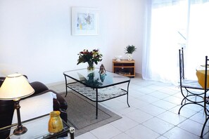 A modern living room with a glass coffee table, a sofa, a lamp, and a small decorative statue.