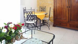 A dining area with a table set for four, surrounded by chairs, a wooden cabinet, and a glass table with a floral pattern. - Apartment in Caderousse with Pool (Caderousse)