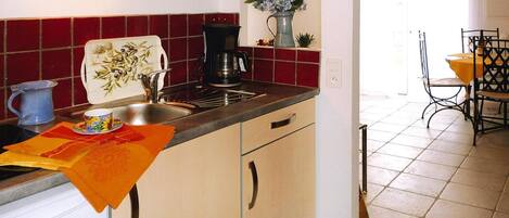 A kitchen with a sink, a coffee maker, and a vase with flowers on the counter.