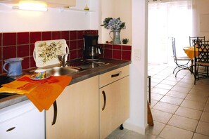 A kitchen with a sink, a coffee maker, and a vase with flowers on the counter.
