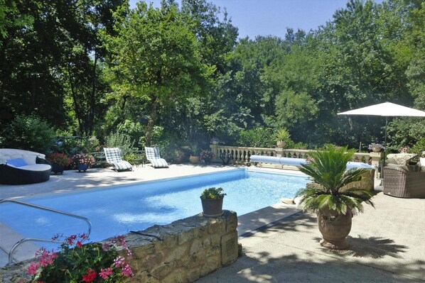 A swimming pool with lounge chairs and potted plants.