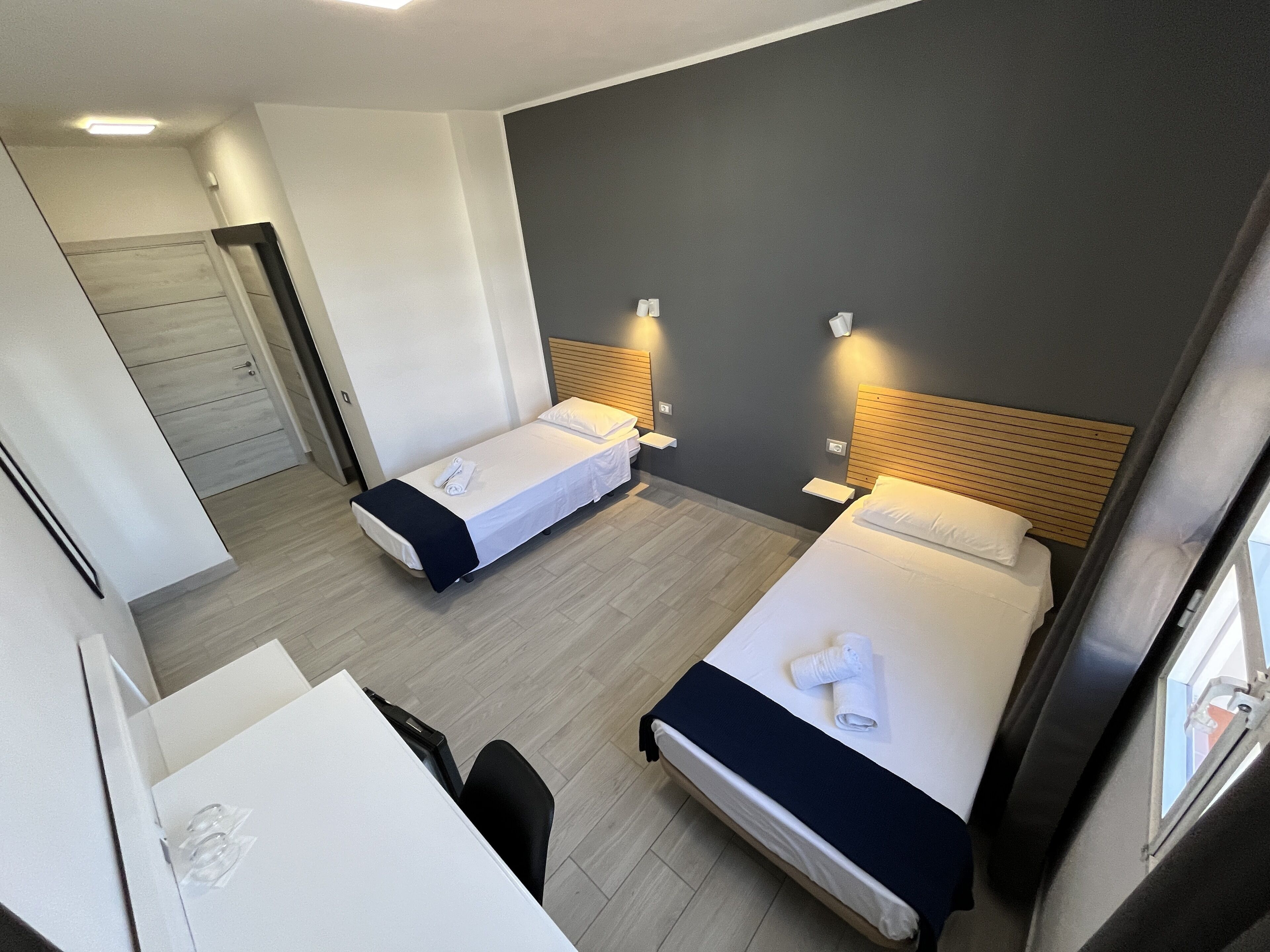 Ein Hotelzimmer mit zwei Einzelbetten, einem Schreibtisch und einem Stuhl.