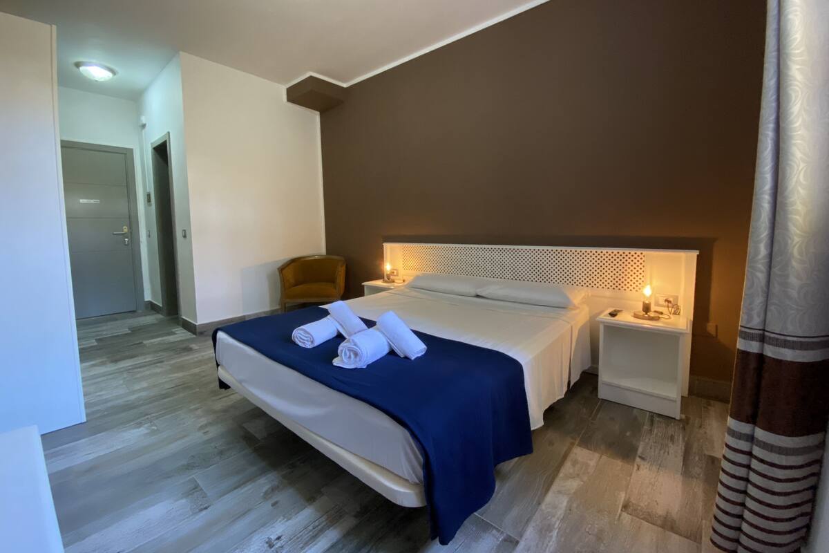 A hotel room with a bed, a nightstand, a chair, and a door.