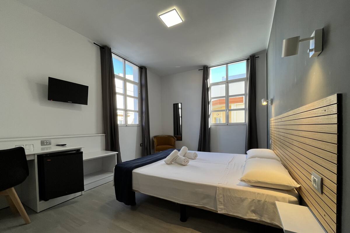 A modern hotel room with a bed, desk, and chair.
