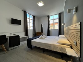 Una habitación de hotel moderna con cama, escritorio y silla.