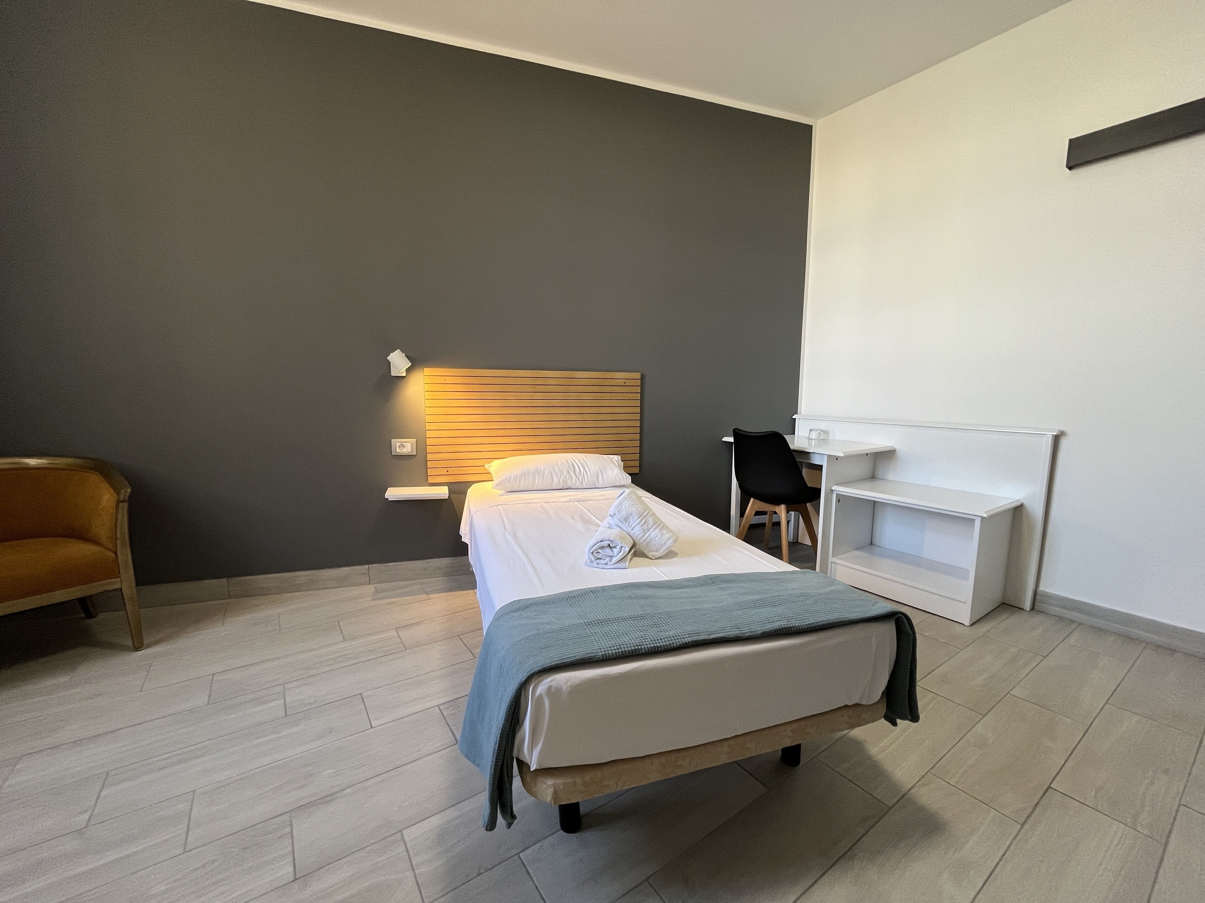 A modern hotel room with a bed, a desk, and a chair.