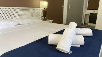 Ein ordentlich gemachtes Bett mit weißen Leinen, einer blauen Tagesdecke und gefalteten Handtüchern.