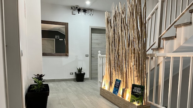 A hallway with a wooden decorative panel, potted plants, and a staircase. - Pensión Cassandra (Arona)