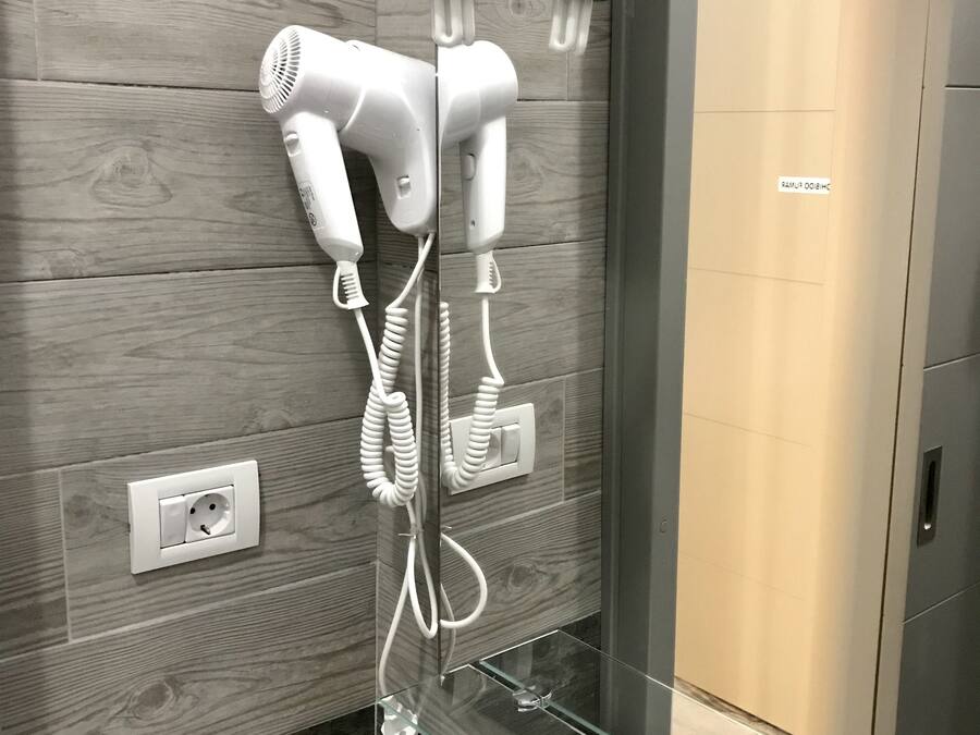 Een moderne badkamer met een houten wand, een douchecabine van glas en een witte wastafel.