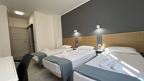 A hotel room with three single beds, a desk, and a chair. - Pensión Cassandra (Arona)
