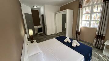 Une chambre d’hôtel avec un lit, un bureau, une lampe, une fenêtre avec des rideaux et une vue sur l’extérieur.