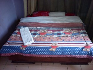 A bed with a striped bedspread, pillows, and a folded towel. - Ikons Hotel & Accommodation (Kiambu)