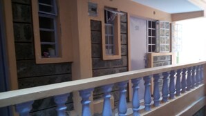 Fachada de edificio con barandilla de balcón, ventanas y pared de piedra.