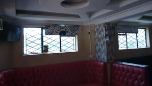 Un interior de restaurante con asientos tapizados en rojo, ventanas con diseño y un techo con iluminación empotrada.