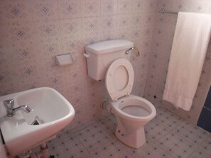 A bathroom with a toilet, sink, and patterned tiles. - Ikons Hotel & Accommodation (Kiambu)