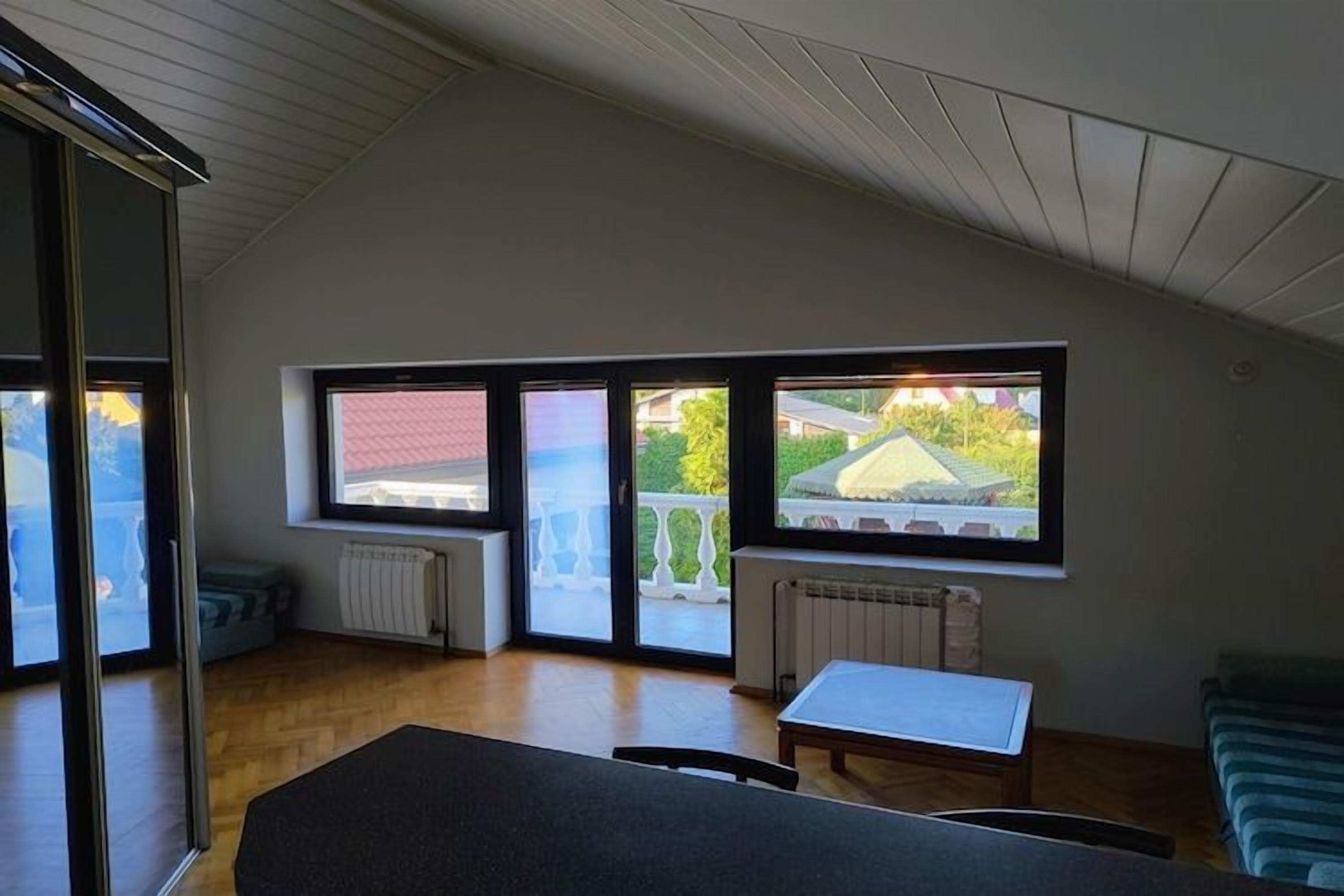 Huoneessa on suuri ikkuna, patteri, pöytä ja tuoli.