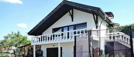 Ein zweistöckiges Haus mit Balkon, Garage und Trampolin im Garten.