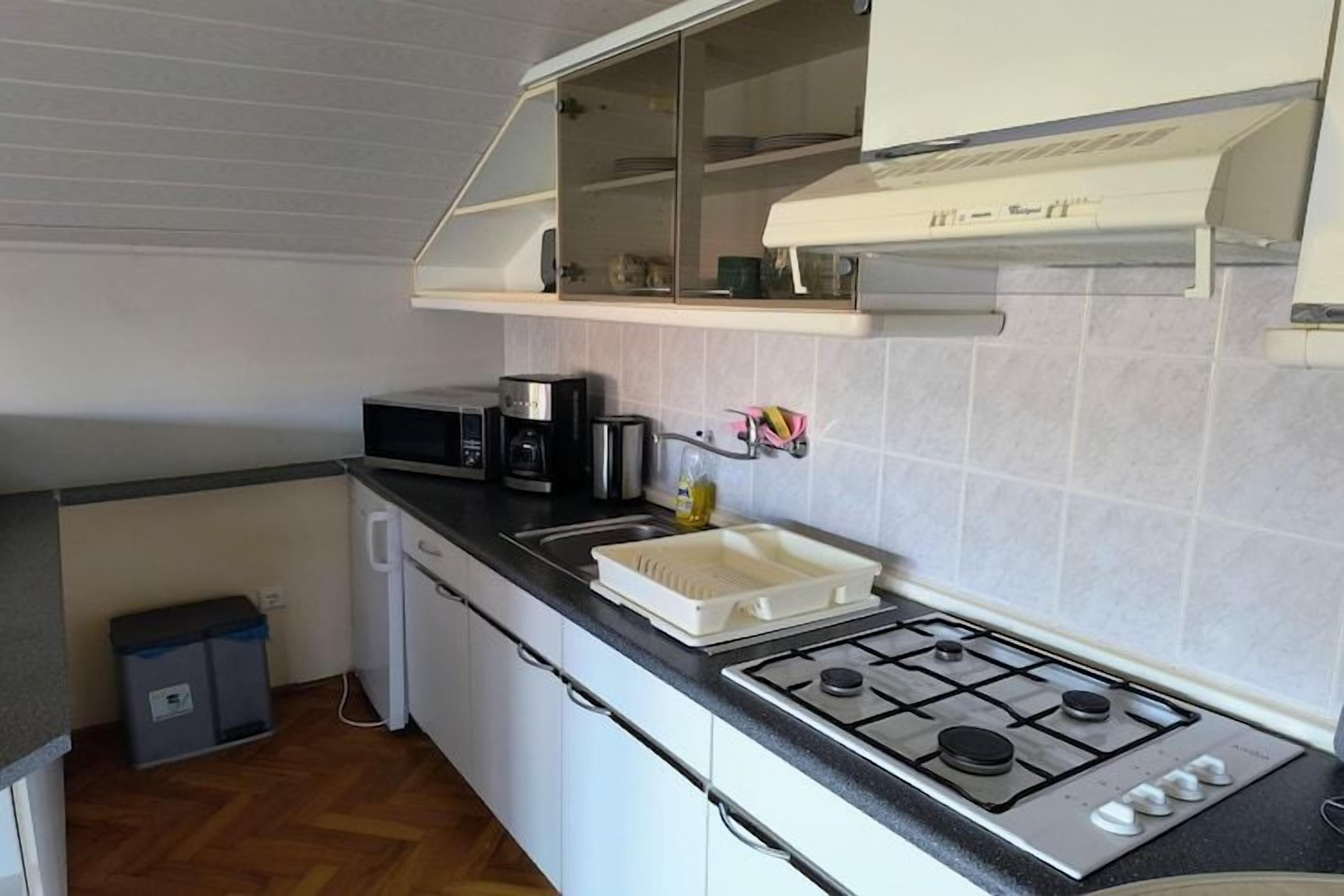 Cocina compacta con estufa a gas, microondas y un lavamanos pequeño.