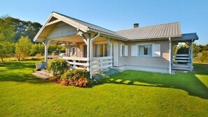 Une maison de plain-pied avec un porche abrité, un petit jardin devant et un ciel bleu dégagé.