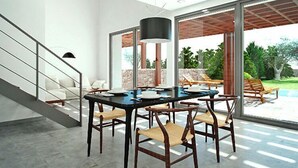 Un comedor moderno con una mesa negra y sillas de madera, ventanas amplias y vistas a un jardín y piscina.
