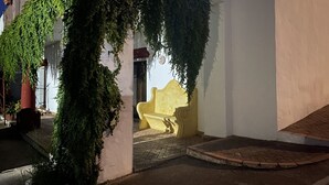 A building with a yellow bench under a vine-covered archway. - Apartamentos Turísticos Los Alisos (Aliseda)