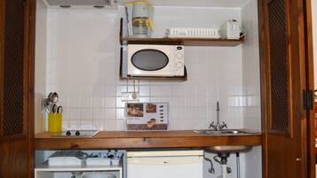 A compact kitchen with a microwave, coffee maker, and a small sink.