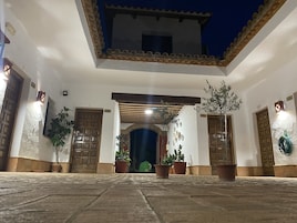 Un patio con suelo de baldosas, plantas en macetas y puertas de madera.