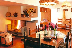 A dining area with a fireplace, wooden furniture, and wine bottles. - Estate in Montaione with Pool & Wine Tasting (Montaione)