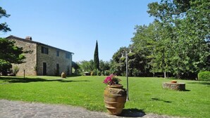 A stone building with a paved pathway leading to a large terracotta pot with flowers. - Estate in Montaione with Pool & Wine Tasting (Montaione)