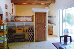 A kitchen with a wooden door, tiled backsplash, and a window providing natural light. - Cozy Noves Home with Pool Access (Noves)