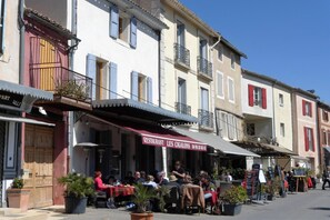 A street with outdoor seating at a restaurant named 'RESTAURANT LES CIGALONS'.