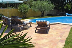 A swimming pool area with lounge chairs and a covered umbrella. - Cozy Noves Home with Pool Access (Noves)