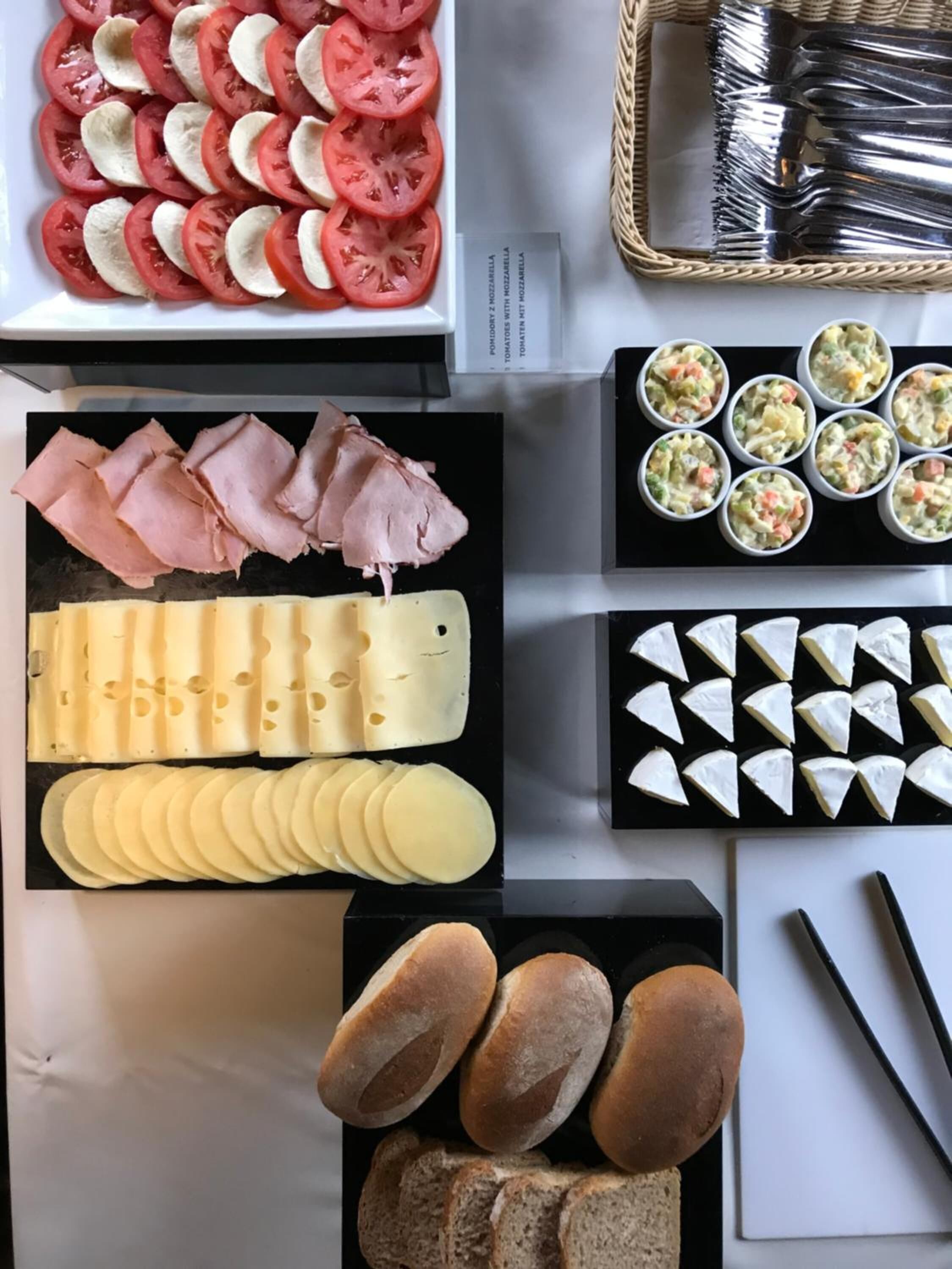 Variedad de alimentos como rodajas de tomate, jamón, queso y pan sobre una mesa.