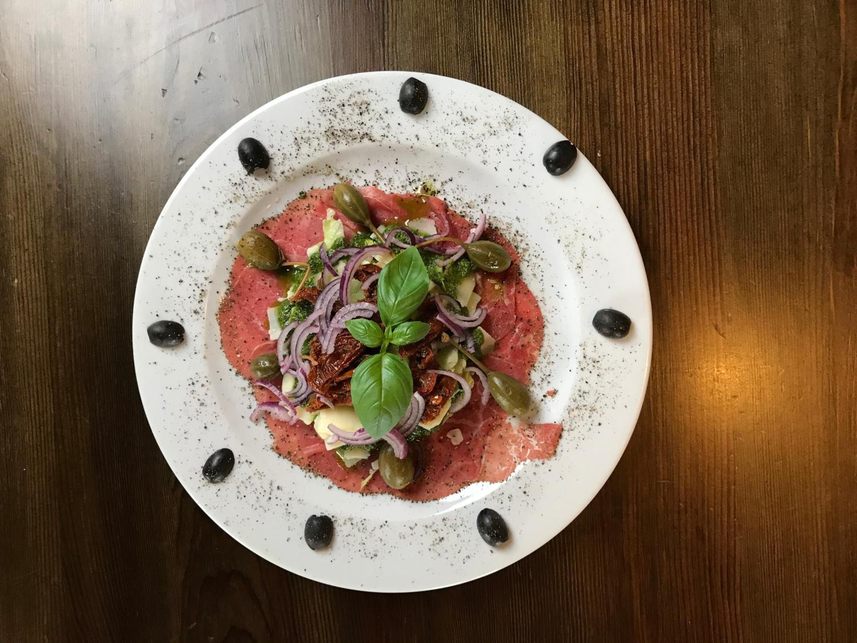 Un plato blanco con ensalada sobre una mesa de madera.